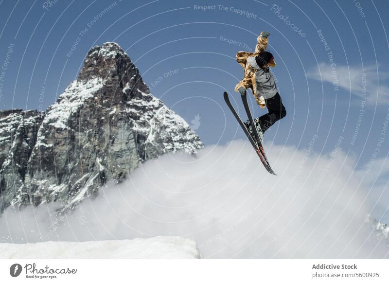 Anonymer Mann springt mit Snowboard auf Schweizer Alpen gegen blauen bewölkten Himmel anonym springen Snowboarder Schnee Berge u. Gebirge Blauer Himmel