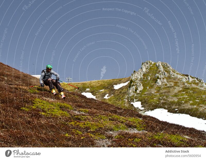 Junger Mann in Freizeitkleidung beim Skifahren auf einer Wiese im Urlaub in den Schweizer Alpen Wanderer Gras Hügel Ganzkörper sorgenfrei wandern Skifahrer Mast