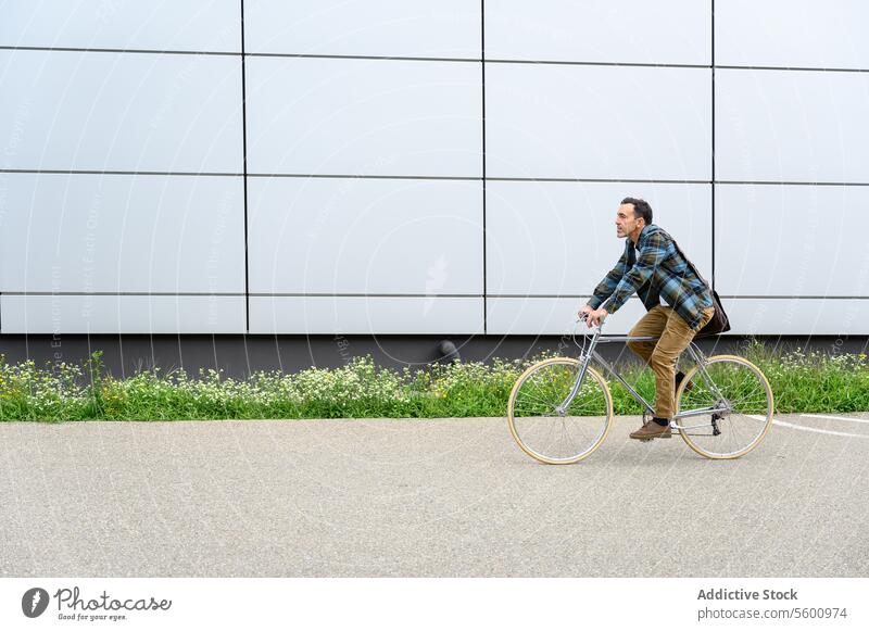 Junger Mann mit Fahrrad auf der Straße Mitfahrgelegenheit urban Großstadt Gebäude Verkehr Fahrzeug Stil modern Wand Zeitgenosse trendy Spaziergang Zyklus