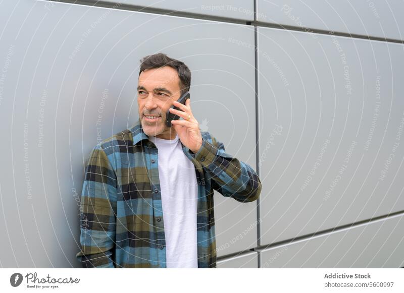Lächelnder Mann, der mit seinem Smartphone spricht reden männlich Gespräch sprechen Telefonanruf Apparatur Kommunizieren Anruf benutzend Gerät heiter Talkrunde