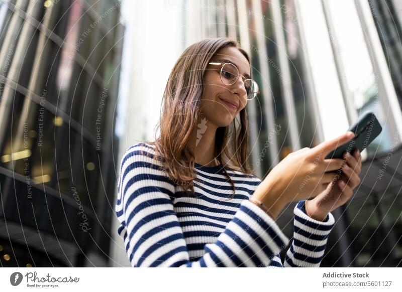 Junge Frau mit Smartphone in Londoner Stadtumgebung urban Gebäude Lächeln Technik & Technologie Mitteilung Großstadt modern Architektur jung Erwachsener