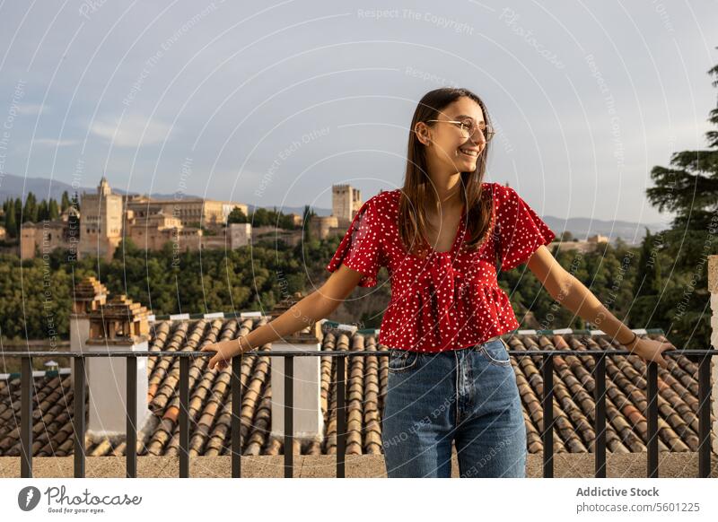 Glücklicher Tourist, der am Geländer der historischen Alcazaba steht, während er seinen Urlaub in Granada, Spanien, genießt Frau Brille Lächeln Freizeitkleidung