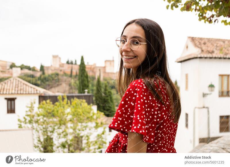 Lächelnder Tourist, der vor der Alcazaba in der Stadt steht und in die Kamera schaut Frau historisch Baum Seitenansicht Freizeitkleidung erkunden reisen