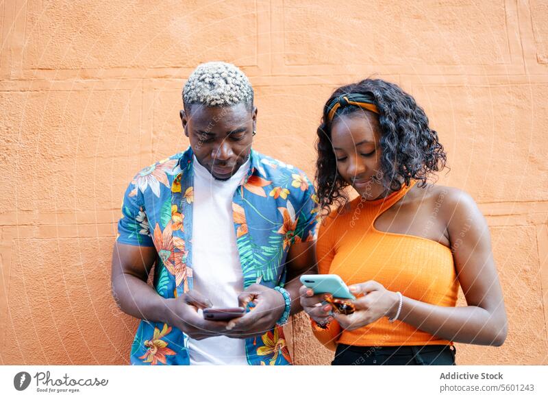 Junge schwarze Freunde benutzen Smartphone auf der Straße jung Paar Lächeln Glück Lifestyle im Freien Telefon Mobile Technik & Technologie urban lässig Mann