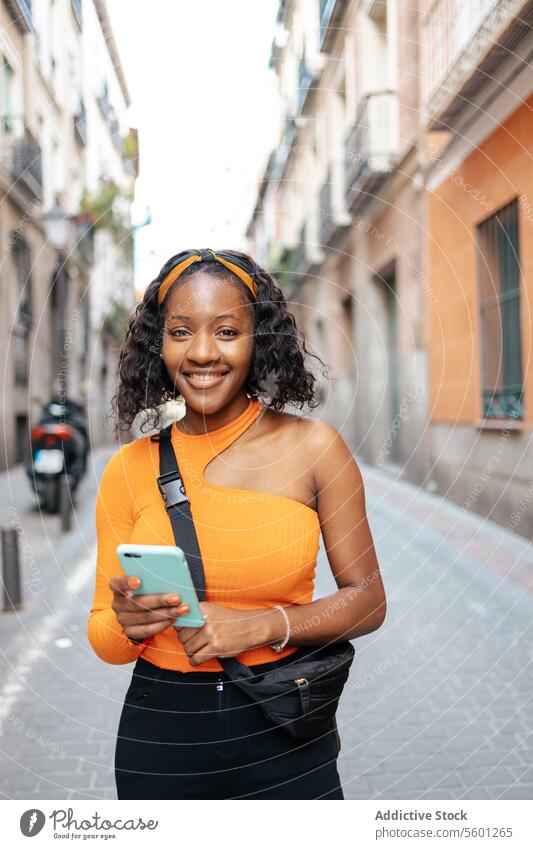 Porträt einer jungen schwarzen Frau, die ihr Smartphone auf der Straße benutzt Lifestyle Glück Technik & Technologie Texten Lächeln Mobile Person Telefon schön