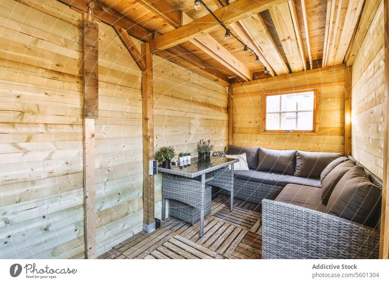 Holzhütte mit grauer Couch und Couchtisch Kabine hölzern Wohnzimmer Liege Kaffeetisch Zimmerpflanze Fenster Loft Innenbereich Sofa Kopfkissen lebend Raum