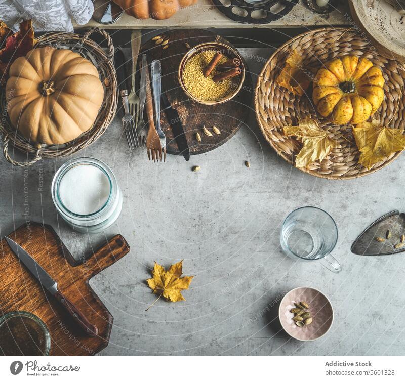 Herbstliches Essen Hintergrund mit Kürbissen, Schneidebrett und Messer, verschiedene Gewürze und Küchenutensilien. Ansicht von oben Lebensmittel Utensilien