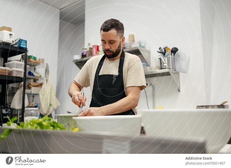 Junge Köchin rührt mit Kochstab Küchenchef Essen zubereiten mitreißend Lebensmittel professionell Restaurant Gemüse Mann jung Arbeit männlich Speise Person