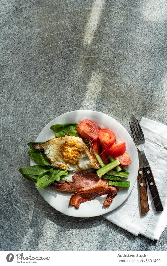 Von oben auf den gesunden Frühstücksteller mit Ei und Speck Teller Gesundheit Gemüse Tomate Salatgurke Spinat gebraten weiß Knusprig frisch Blätter