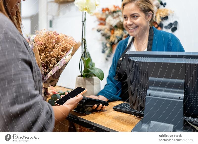 Kunde beim kontaktlosen Bezahlen in einem Blumenladen Frau Zahlung berührungslos Smartphone nfc Technik & Technologie Blumenhändler Kassierer assistierend Kasse