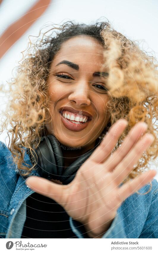 Fröhliche ethnische Frau mit Kamera Kopfhörer heiter Glück krause Haare Lächeln Selfie Afroamerikaner positiv schwarz Apparatur Freude Gerät Musik Zusammensein