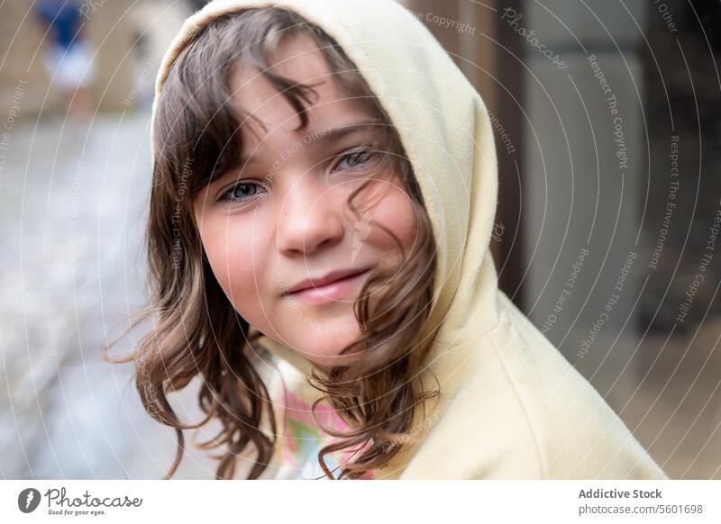 Lächelndes Kindermädchen mit Kapuze schaut in die Kamera Porträt im Freien Regen Glück Jugend heiter Unschuld Freude Gesicht lässig Bekleidung Mädchen niedlich