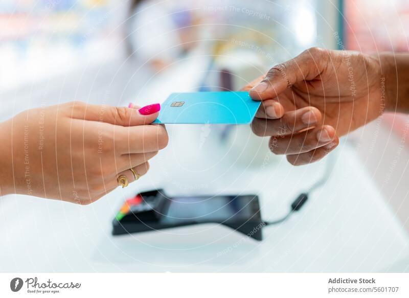 Anonyme Hände, die eine Kreditkarte in einer Drogerie halten Kunde Frau Kassierer blau Chip Hand Ernte anonym Geben Zahlung Kasse Dienst Apotheke Laden