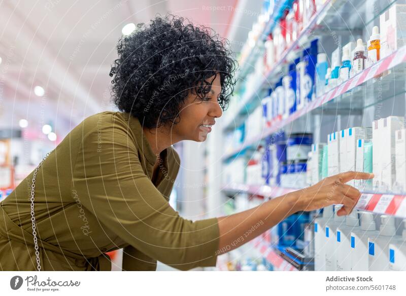 Frau sucht in einem Geschäft Medikamente aus den Regalen Kunde Suche Produkt Drogerie selbstbewusst hockend Gang Apotheke Laden Medizin kaufen Käufer Werkstatt