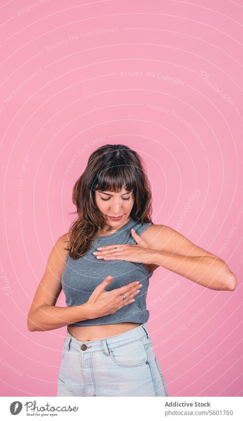 Frau bei einer Brust-Selbstuntersuchung zur Überprüfung von Brustveränderungen auf rosa Hintergrund. Leerzeichen kopieren bse Bewusstsein für Brustkrebs