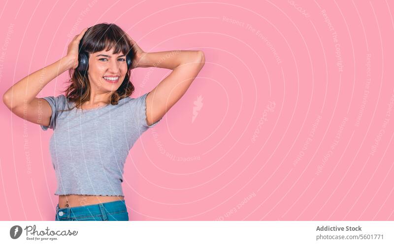 Glückliche Frau mit Kopfhörern, die Musik hört, isoliert auf rosa Hintergrund. Studioaufnahme. Raum kopieren modern Drahtlose Technologie Erwachsener attraktiv