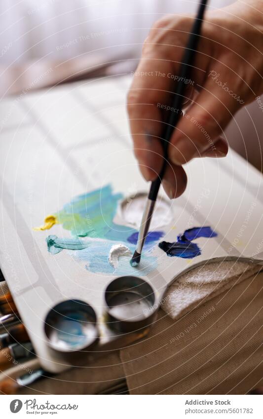 Nahaufnahme einer Hand mit einem Pinsel auf einer Farbpalette unkenntlich Anstreicher Palette Bürste Leinwand Künstler Malerei Farbe kreativ Kunstwerk