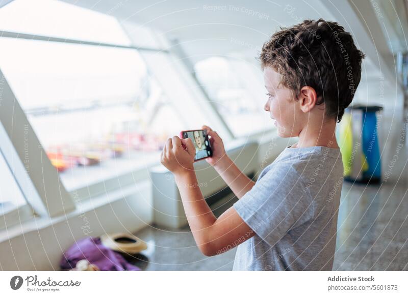 Niedlicher Junge bei Videoanruf über Smartphone Mobile niedlich Flughafen Seitenansicht Zeitgenosse Anschluss reisen Urlaub Feiertag Telefon Beteiligung Lächeln