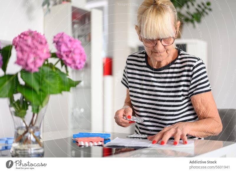 Ältere Frau bereitet Pillenbox zu Hause vor Tablette lesen Senior Medizin Brille untersuchen geduldig Fokus Medikament älter vorbereiten Konzentration gealtert