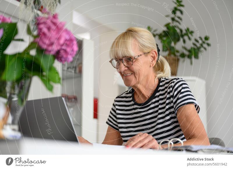 Glückliche reife Frau mit Laptop im Wohnzimmer zu Hause freiberuflich benutzend heimwärts abgelegen Arbeit Projekt positiv Browsen Gerät Apparatur online