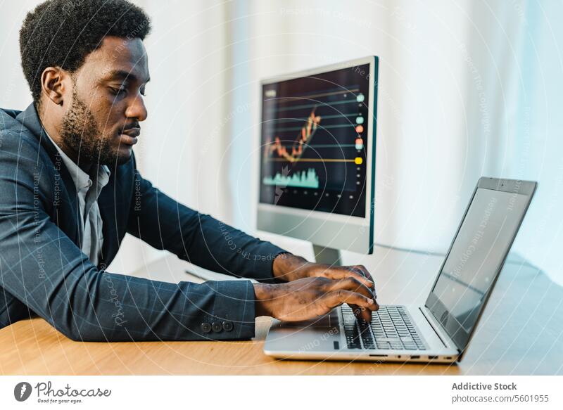 Fokussierter männlicher Händler mit Laptop Mann binär Option Makler Handel Browsen benutzend finanziell schwarz Afroamerikaner ethnisch Grafische Darstellung
