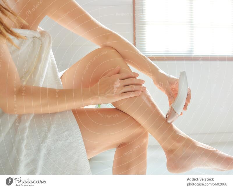 Junge kaukasische Frau enthaart ihr Bein mit einem elektrischen Epiliergerät im Badezimmer. Rasieren Körper heimwärts Mädchen Spa benutzend danach depil