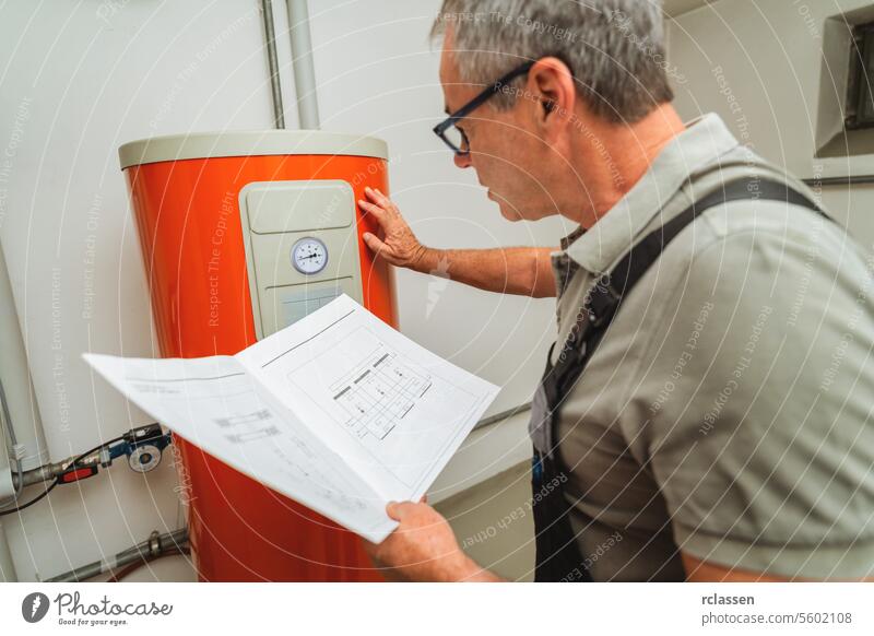 Heizungstechniker überprüft eine alte Gasheizung mit einer Papieranleitung in einem Heizungsraum in einem Haus. Gasheizung Ersatz Verpflichtung Konzept Bild