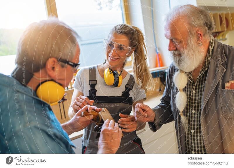 Generationen von Schreinern diskutieren in der Werkstatt ihres Familienunternehmens über die Verwendung eines Handhobels Bildung Kapselgehörschützer