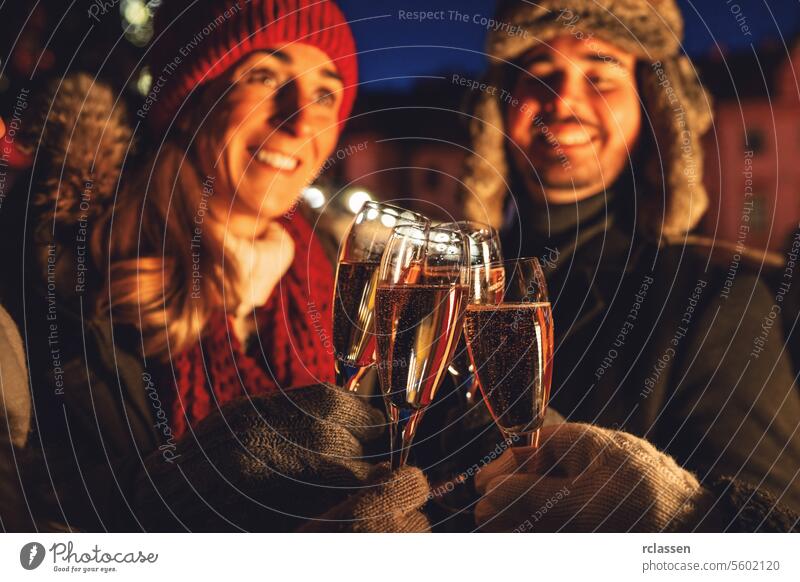 Ehepaar stößt mit Sektgläsern auf einem Weihnachtsmarkt an Menschengruppe Freunde Neujahr Paar Champagne Röstung Winter Abend Brille Feier Glück Freude