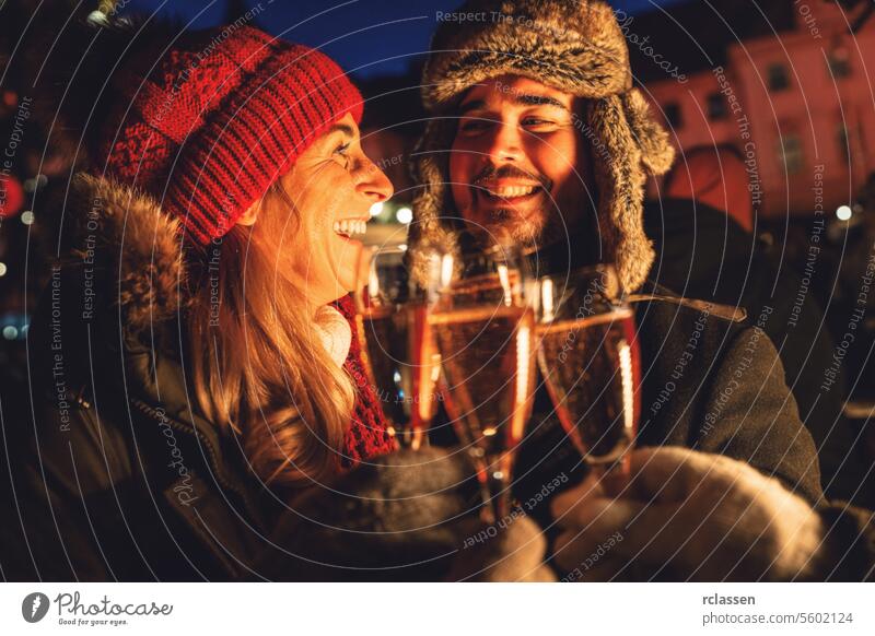 Lächelndes Paar stößt am Silvesterabend mit Sektgläsern an Menschengruppe Freunde Neujahr Weihnachtsmarkt Champagne Röstung Winter Abend Brille Feier Glück