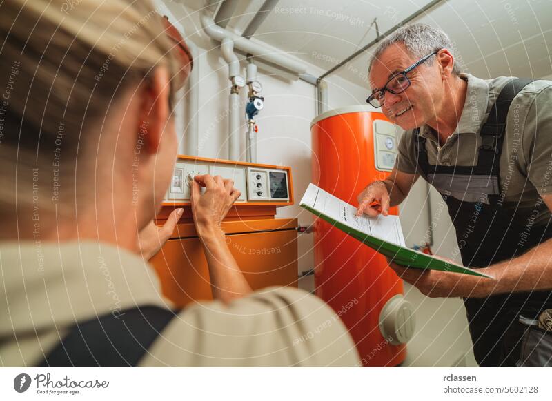 Ein Team von Heizungsmonteuren überprüft eine alte Gasheizung mit einer Papieranleitung in einem Heizungsraum in einem Haus. Gasheizung Ersatz Verpflichtung Konzept Bild