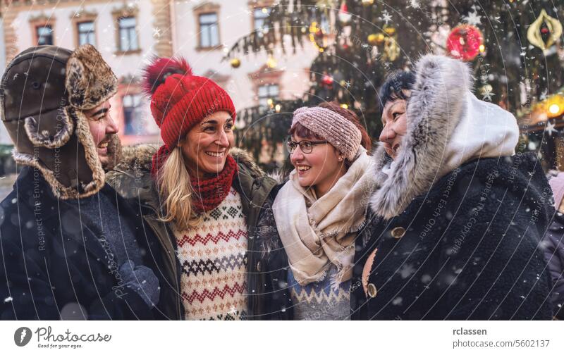Freunde lachen zusammen auf einem verschneiten Weihnachtsmarkt Sitzung Frohe Weihnachten Tasse Kakao Handschuhe traditionell Glühwein Deutsch Schneeflocken
