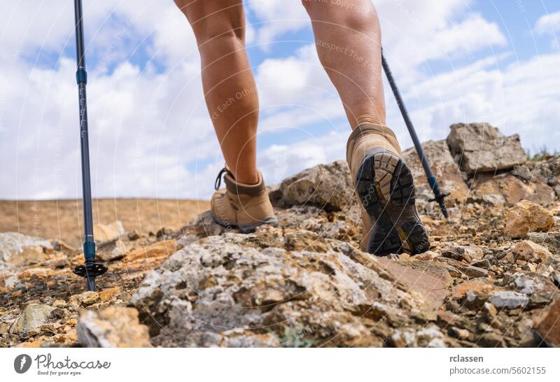 Nahaufnahme der Beine eines Wanderers mit Trekkingstöcken auf einem felsigen Pfad Fuerteventura felsiger Pfad Abenteuer Outdoor-Aktivität Wanderschuhe laufen