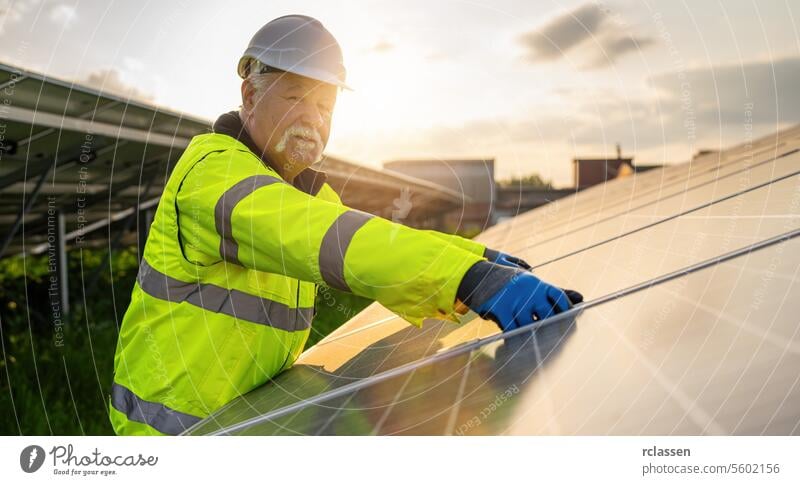 Älterer Ingenieur bei der Montage von Solarzellen in einem Energiepark bei Sonnenuntergang. Alternative Energie ökologisches Konzept Bild. Technik & Technologie