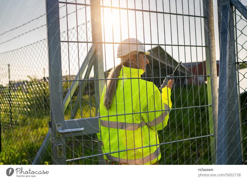 Technikerin mit Walkie-Talkie auf dem Weg zum Tor eines Solarfelds Technik & Technologie Pflanze Industrie Elektrizität Arbeiter Sicherheit Ingenieur ökologisch