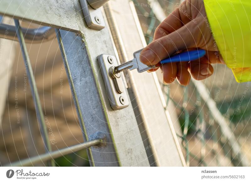 Handentriegelung eines Metalltors mit Schlüssel, Fokus auf Schloss und Schlüssel Taste freischalten Sicherheit Zugang Eingang Schlüsselloch Gate im Freien