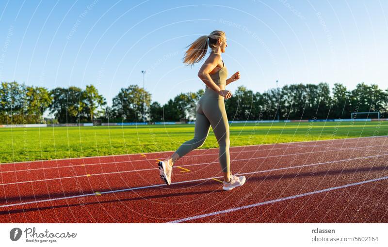 Seitenansicht einer Frau, die auf einer Bahn im Sonnenlicht läuft Veranstaltung Geschwindigkeit Frau läuft Joggen Athlet Sport Gesunder Lebensstil