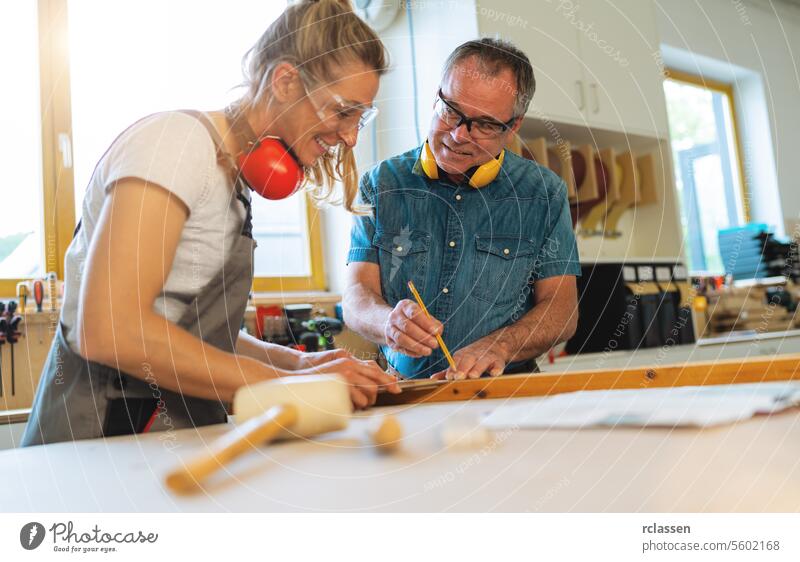 Zwei Zimmerleute markieren Maße auf Holz in einer Tischlerei Hammer professioneller Handwerker Hobelbank Möbelindustrie Arbeiter Schnittholz Schreinerei