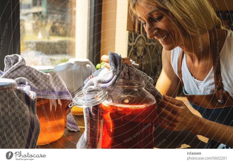 Happy Woman Blick auf Kombucha Tee mit Pilz Schichten in einem großen Glas. organische gesunde Getränk fermentierte Lebensmittel, probiotische Ernährung Getränk für gutes Gleichgewicht Verdauungssystem.