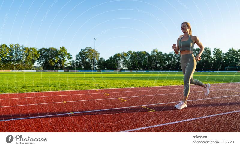 Frau joggt auf einer sonnigen Laufstrecke Veranstaltung Geschwindigkeit Frau läuft Bahn Sonnenlicht Joggen Athlet Sport Gesunder Lebensstil sportliche Kleidung