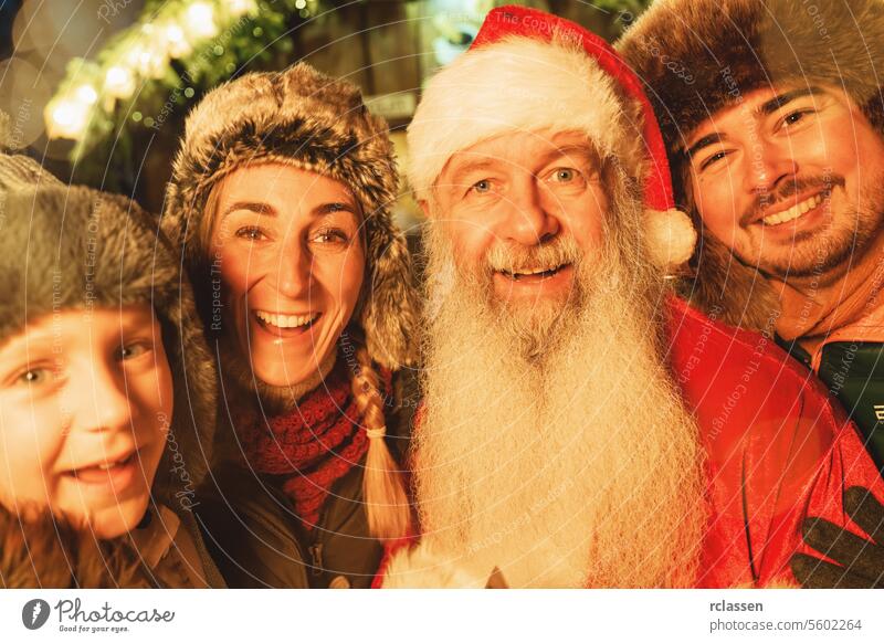 Eine Familie und der Weihnachtsmann verbringen einen glücklichen Moment auf einem Weihnachtsmarkt, der von festlichen Lichtern erleuchtet ist Tourist Tracht