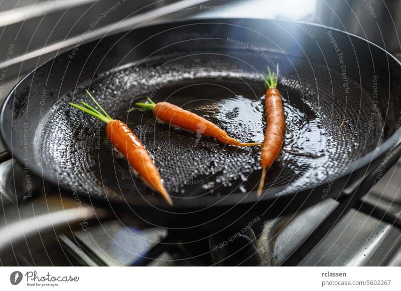 Frische Karotten braten in geölten Pfanne auf einem Gasherd in einer professionellen Küche in einem Restaurant. Luxus-Hotel Kochen Konzept Bild. Gemüse