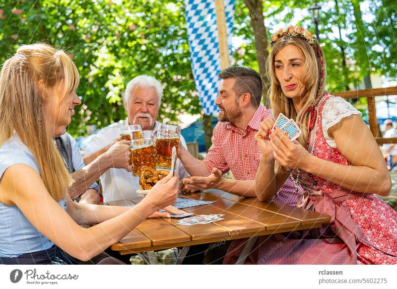 Bayerische Menschen in Tracht spielen das traditionelle Kartenspiel Schafkopf in einem deutschen Biergarten oder auf einem Oktoberfest Glücksspiel Spielen