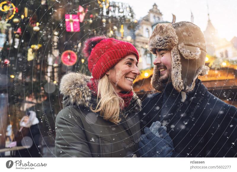 Verliebtes Paar, das sich auf einem verschneiten Weihnachtsmarkt zärtlich anlächelt Freunde Glühwein Vollbart Tourismus Datierung Fairness reisen Glück Liebe