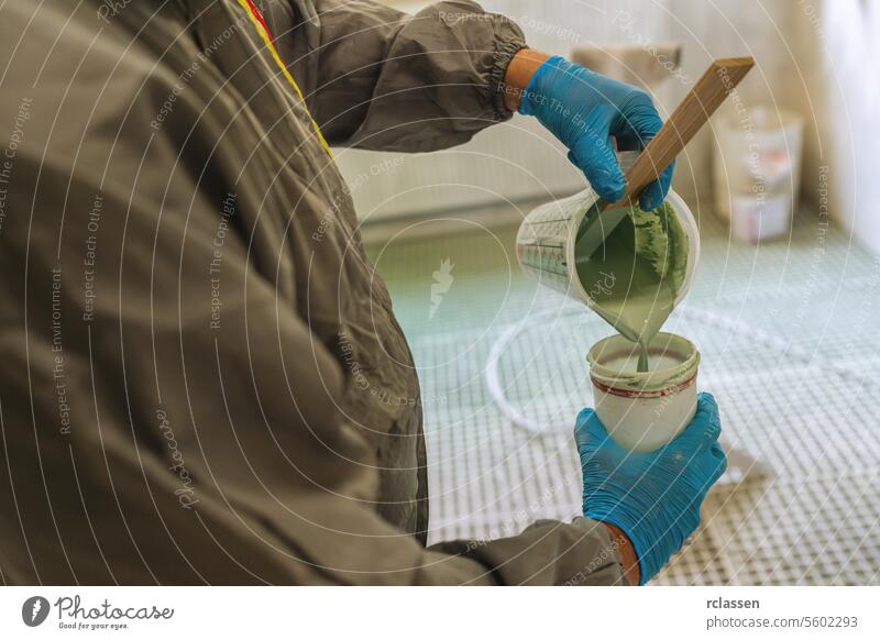 Person in Schutzkleidung gießt grüne Farbe in eine Dose Zimmerer Kunsthandwerker Mundschutz Spritzpistole Anstreicher Gießen Schutzausrüstung Handschuhe