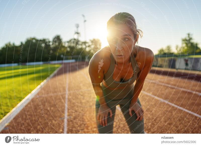 Erschöpfte Frau ruht sich nach dem Training auf einer Laufbahn aus erschöpft Fitness Sport Athlet müde ruhen aktive Kleidung Übung im Freien Sonnenuntergang