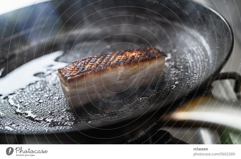 Knuspriger Schweinebraten in heißer Pfanne mit Öl auf einem Gasherd in einer professionellen Küche in einem Restaurant. Luxus-Hotel Kochen Konzept Bild. Kruste