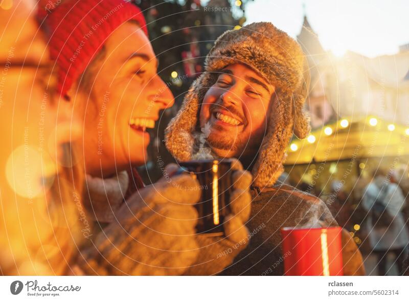 Fröhliche Freunde haben Spaß beim Trinken von Glühwein und heißer Schokolade auf dem Weihnachtsmarkt - Fröhliche junge Leute genießen die Winterferien im Wochenendurlaub