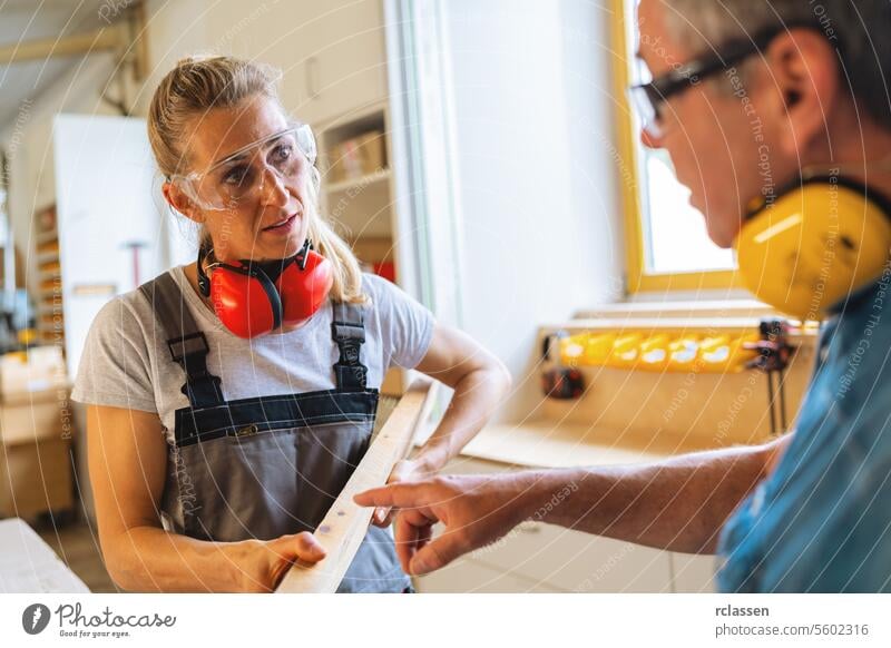 Schreiner und Lehrling prüfen ein Holzbrett in einer Werkstatt professioneller Handwerker Hobelbank Möbelindustrie Arbeiter Schnittholz Schreinerei