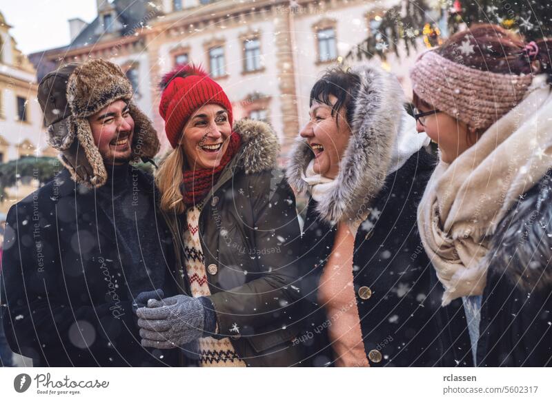 Fröhliche Freunde lachen gemeinsam auf einem verschneiten Weihnachtsmarkt Sitzung Frohe Weihnachten Tasse Kakao Handschuhe traditionell Glühwein Deutsch